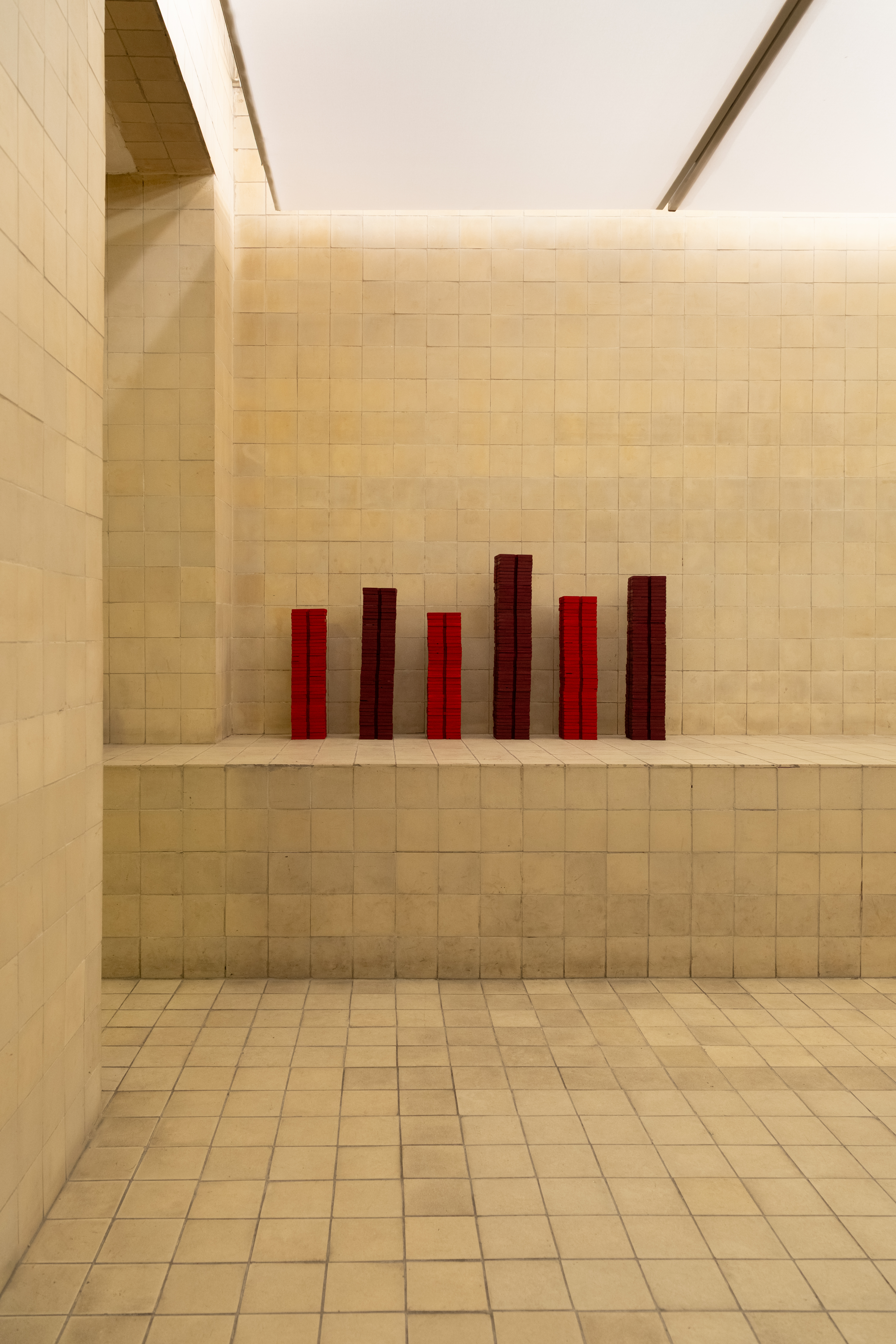 Red lacquer modules arranged as a skyline on a gallery ledge — Bir Arada installation