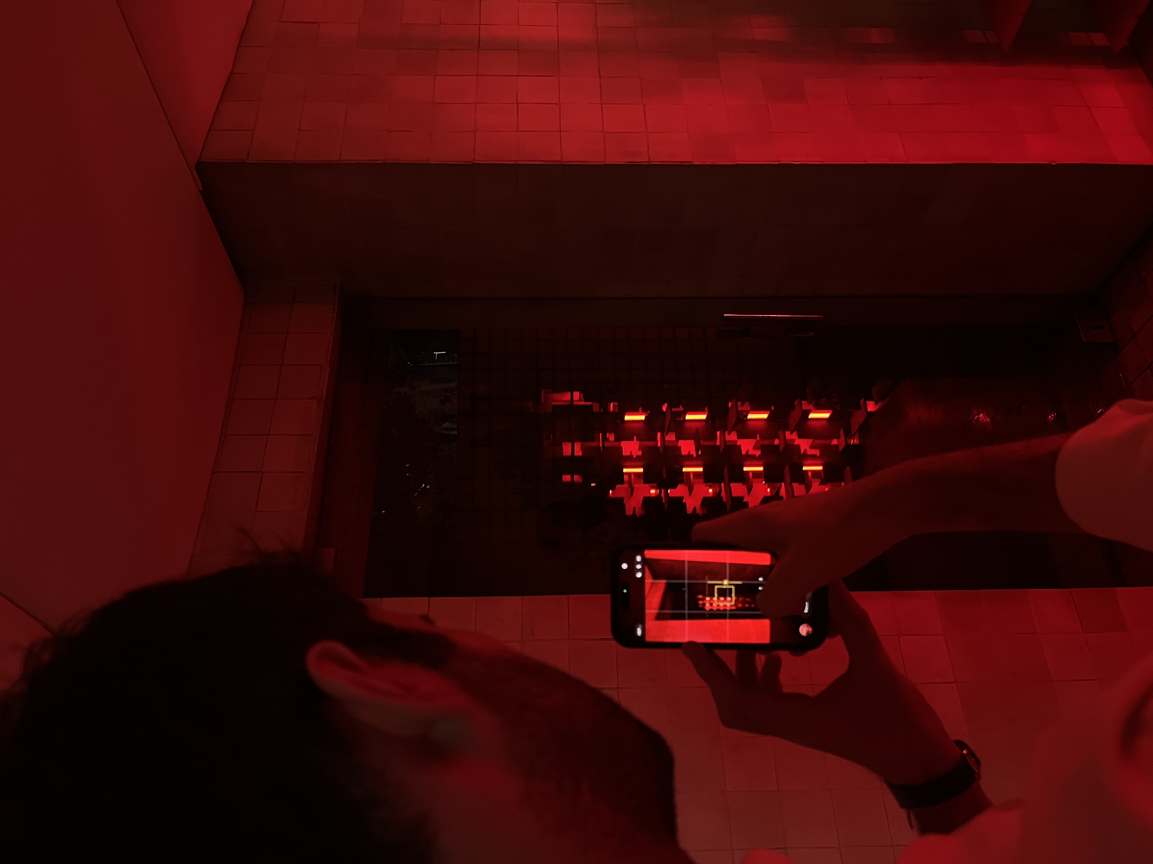 Visitor photographing the red-lit installation — Bir Arada — Together