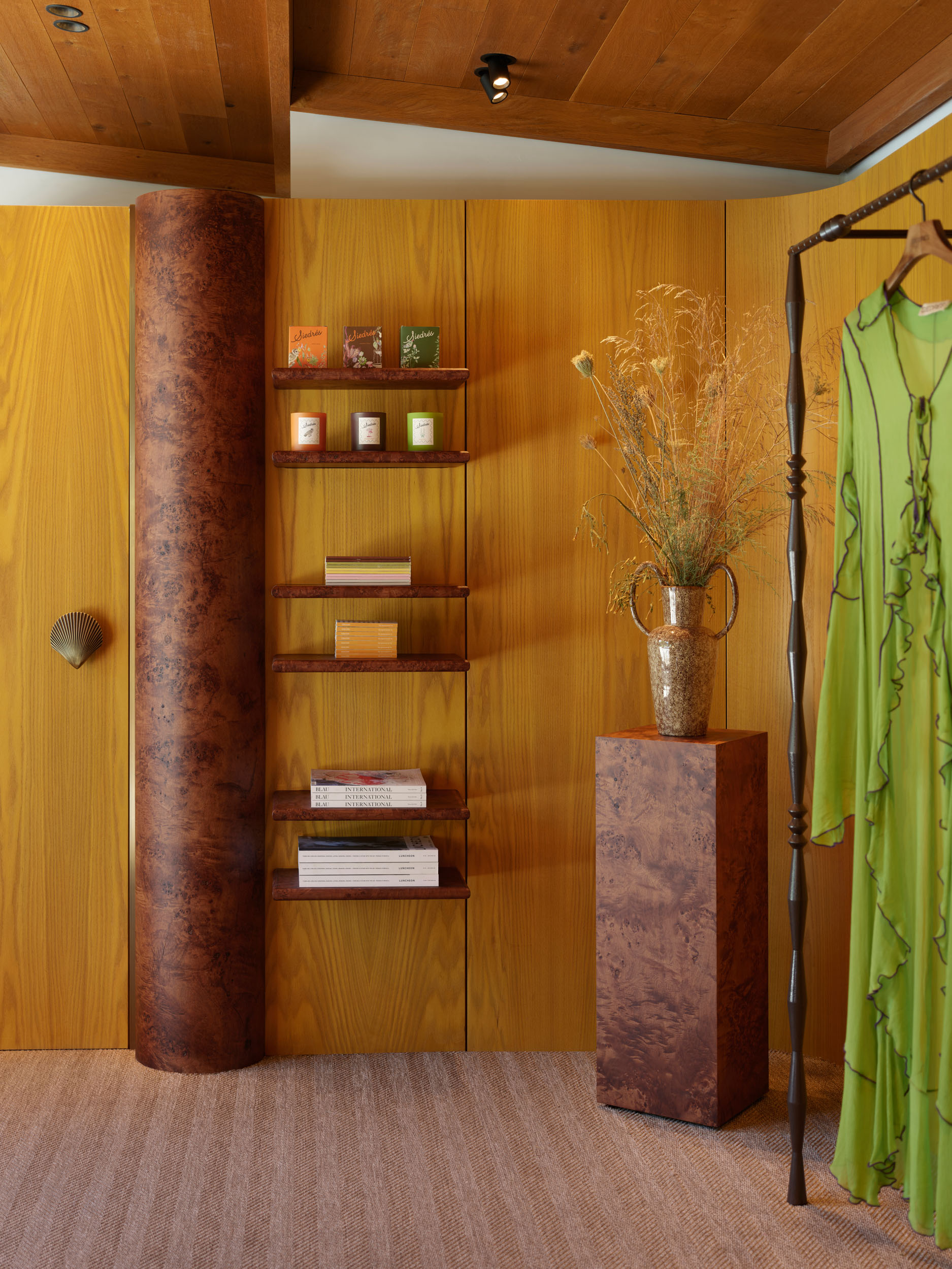 Curved burl-wood column and shelving with resortwear display — Siedrés store interior