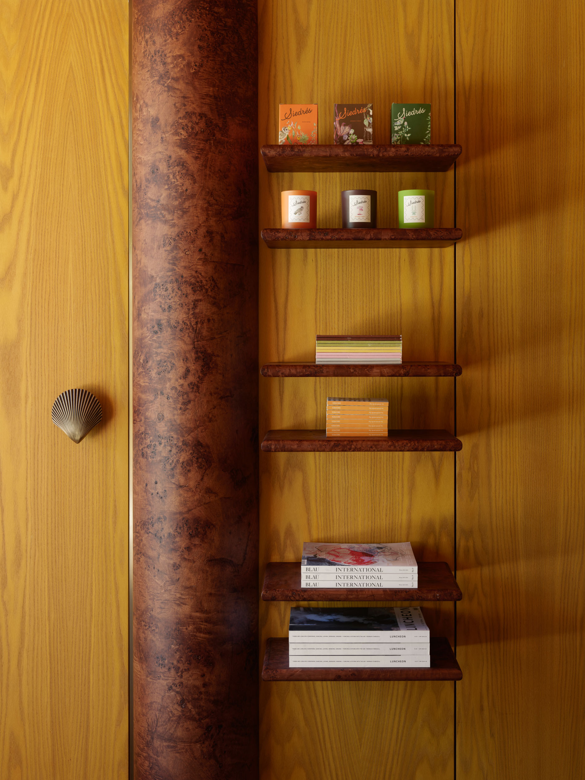 Burl-wood column beside candle and accessories shelving — Siedrés boutique