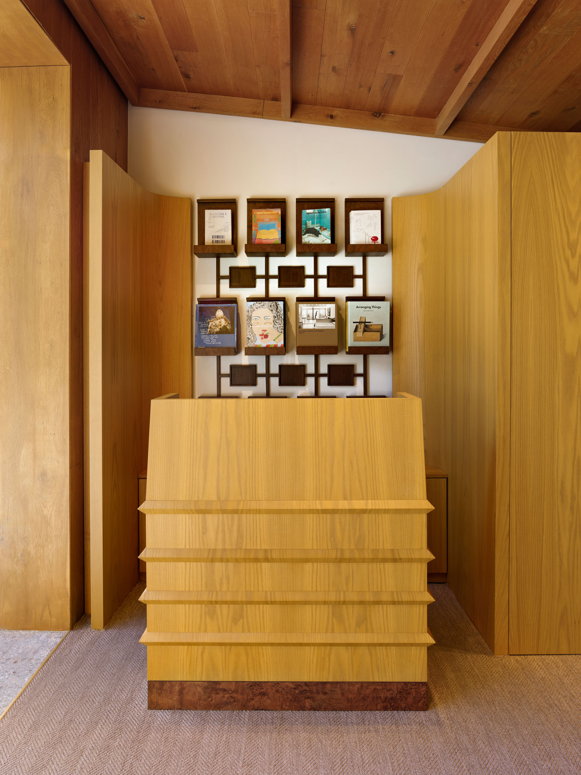 Layered oak cash desk with framed prints wall — Siedrés store interior