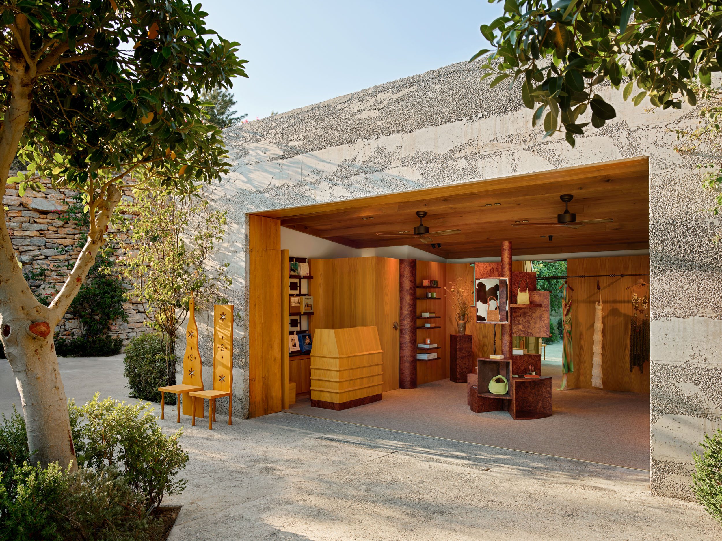 Timber boutique behind a rough stone wall and olive tree — Siedrés store, Turkey