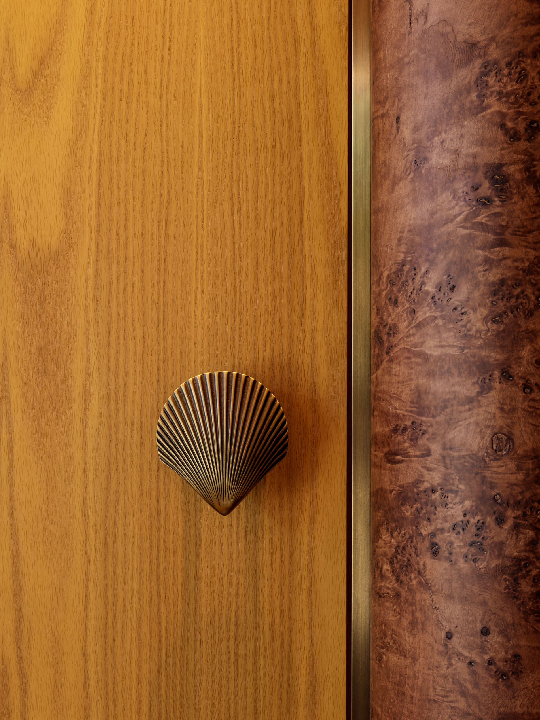 Seashell-shaped bronze handle on an oak door — Siedrés boutique hardware detail
