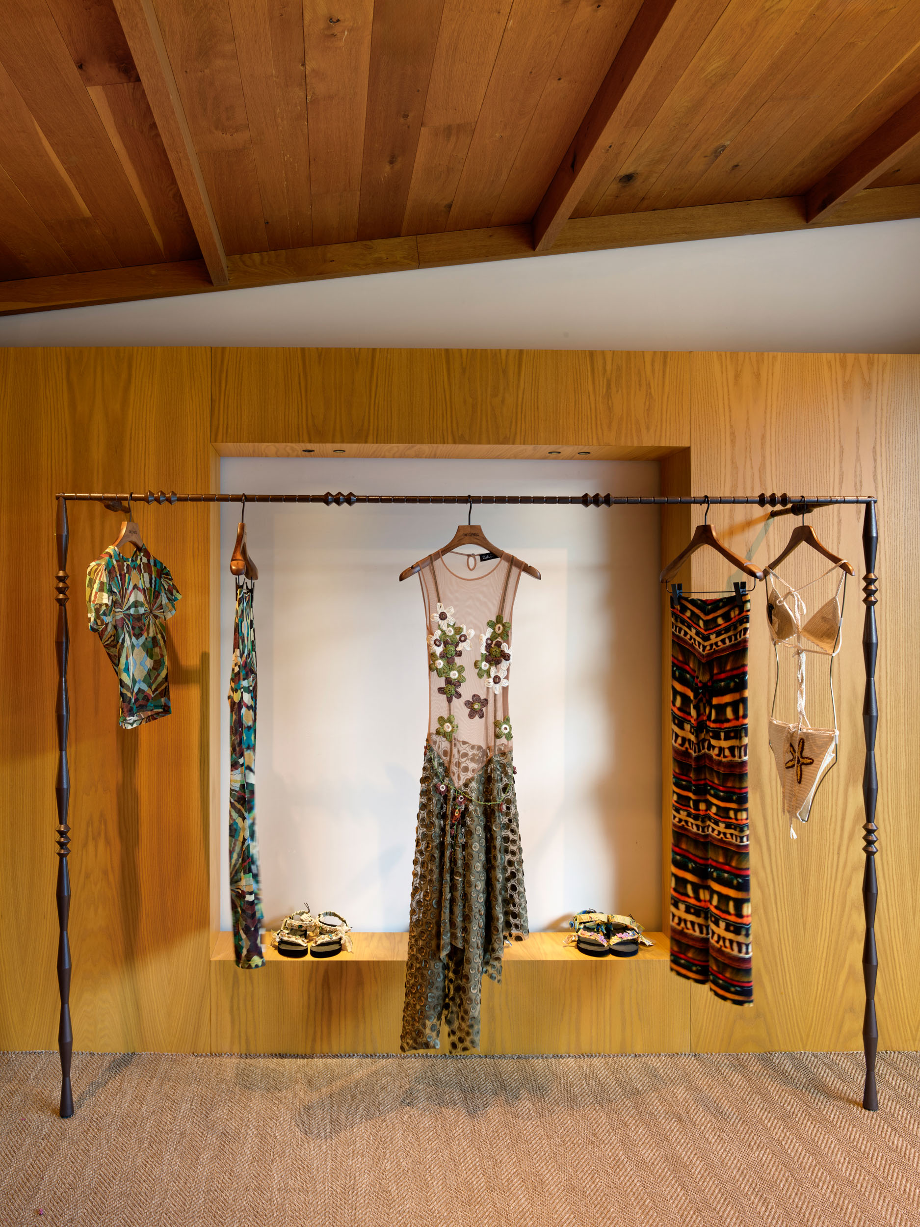 Dresses on a black steel rail within a timber niche — Siedrés retail interior