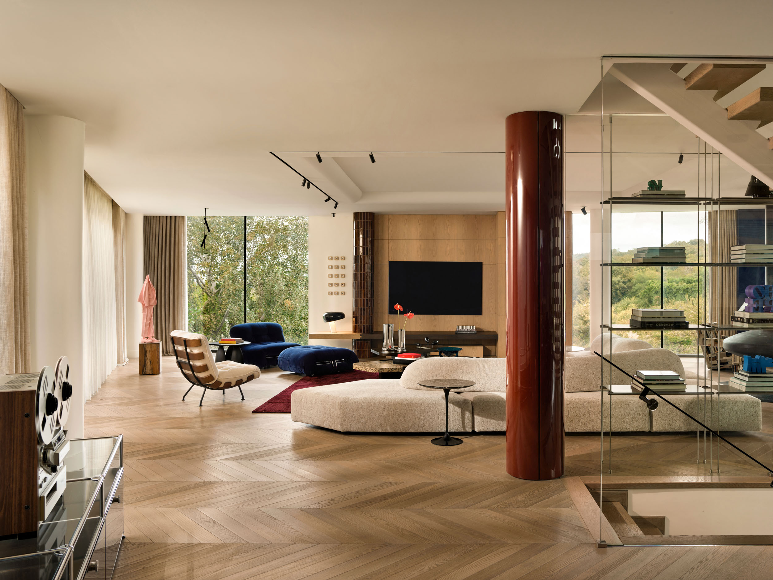 Open-plan living room with glass staircase screen and burgundy column — Zekeriyakoy TP House, Istanbul