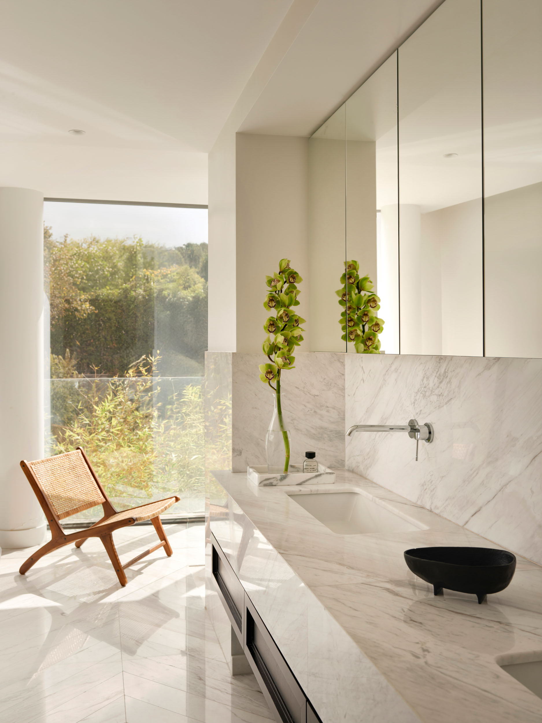 Marble bathroom with wooden lounge chair and garden view — Zekeriyakoy TP House